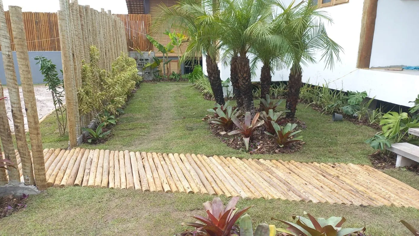 Cerca de bambu com palmeiras e passarela de madeira