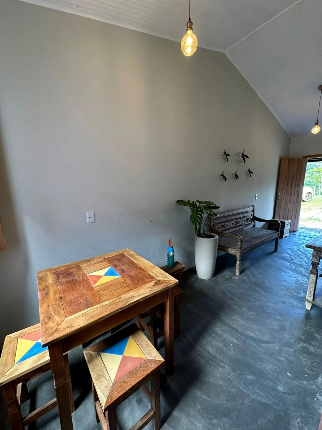 Sala com mesa de madeira colorida e piso de cimento queimado